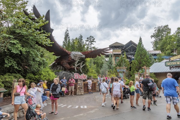 Park guests walk past a large steel sculpture of an eagle near the Wild Eagle wing roller coaster