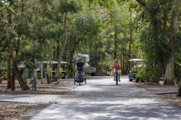 Man and woman ride bicycles through a camping loop at Fort Wilderness campground at Walt Disney