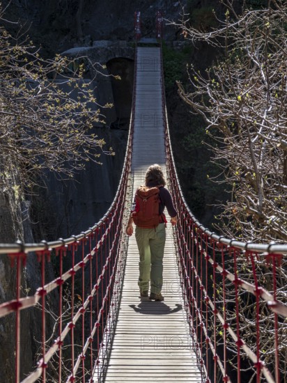 Woman on suspension bridge, hiking path Los Cahorros de Monachil, along the Rio Monachil river,