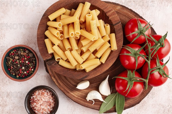 Pasta ingredients spread out, on a wooden surface, with tomatoes and spices, ready to cook, there