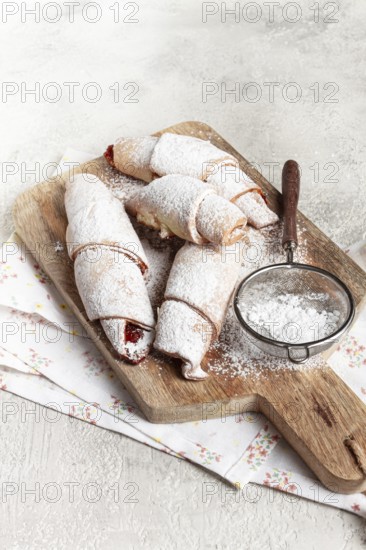 Bagels with filling, sweet pastries, sprinkled with powdered sugar, on a wooden board, dessert,