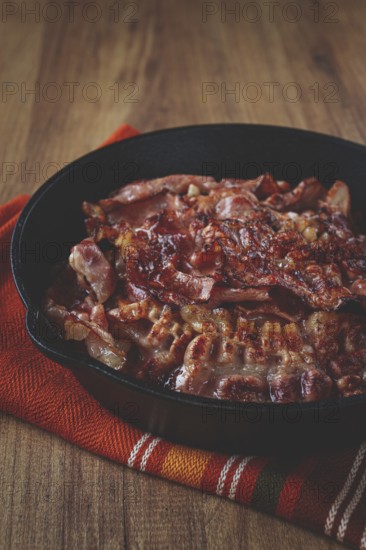 Crispy bacon, on a cast-iron skillet, on a wooden table, rustic style, no people