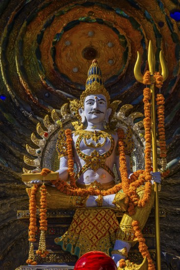 Hindu deity Shiva holding a trident, offerings in the foreground, a cosmic symbol in the back,