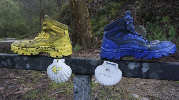 Two hiking boots on a railing decorated with shells, as a guide to Santiago and Fatima, make a