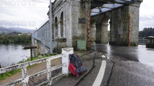 Old stone bridge, with arched construction, a hiking backpack leaning against a railing during a