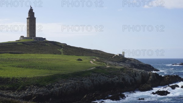 Lighthouse on a grassy cliff overlooking the sea, A Coruna, Spain