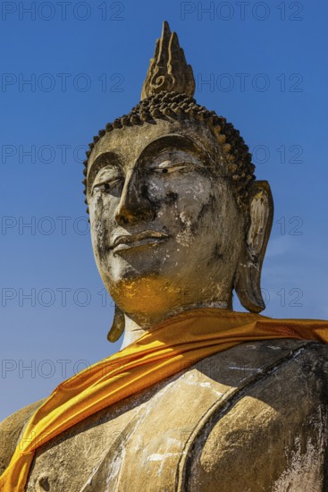 Stone Buddha statue decorated with yellow cloth, historic Buddhist temple complex, Ayutthaya,