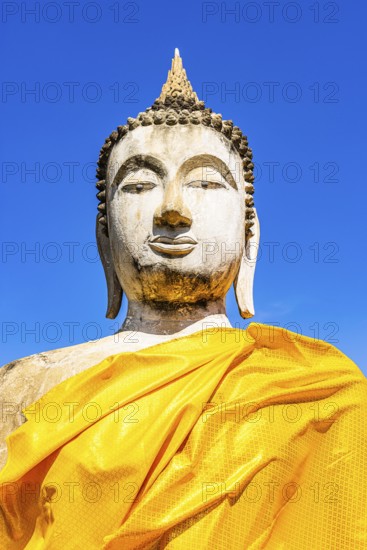Stone Buddha statue decorated with yellow cloths, historic Buddhist temple complex, Ayutthaya,