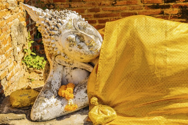 Reclining stone Buddha statue covered with yellow cloth, historic Buddhist temple complex,
