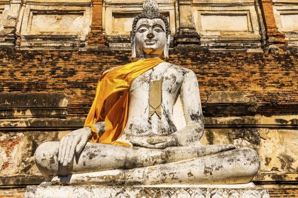 Stone Buddha statue decorated with yellow cloth, historic Buddhist temple complex, Ayutthaya,