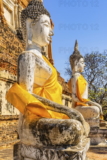 Stone Buddha statues decorated with yellow cloths, historic Buddhist temple complex, Ayutthaya,