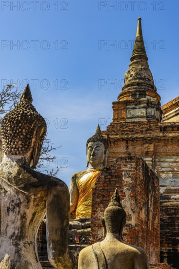 Stone Buddha statues, a high temple tower in the back, Prang, historic Buddhist temple complex,