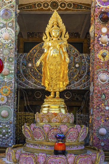 Gilded standing Buddha statue on a base decorated with mosaics and glass works of art, Buddhist
