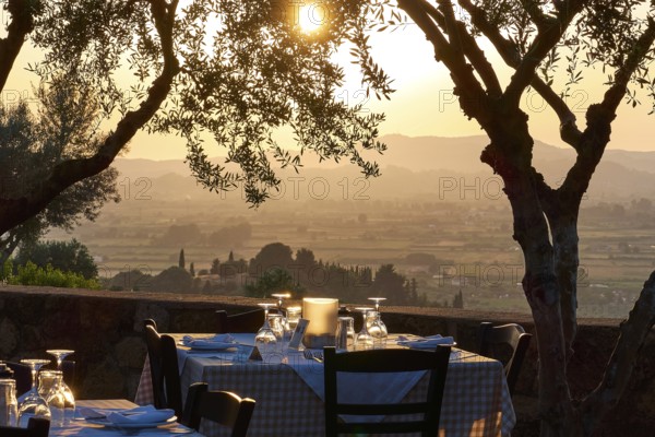 A set table under trees with a view of a vast landscape at sunset, Hotel Europa, garden restaurant