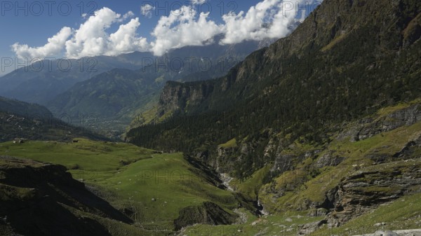 Green valleys and mountains under a partly cloudy sky, trekking in Ladakh, Manali-Leh Highway,