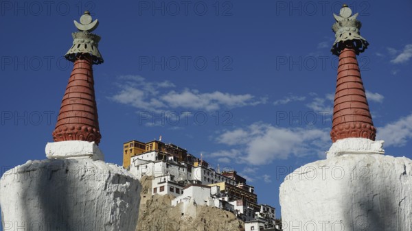 View through two stupas towards Thiksey monastery on a hill under blue sky, Indus Valley, trekking