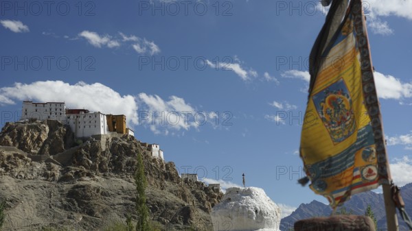 A Buddhist monastery on a hill with a fluttering prayer flag and majestic mountain views, trekking