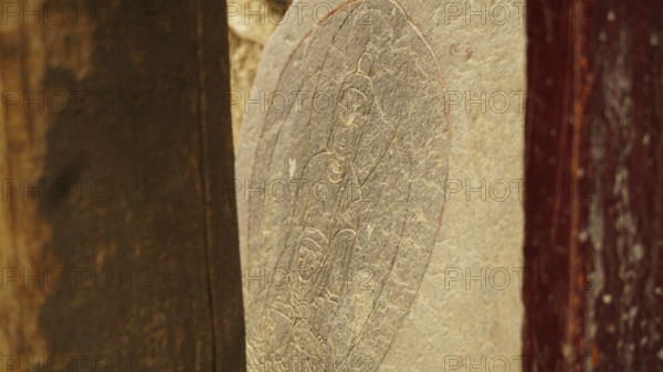 A stone slab with carved Buddha relief as a sacred work of art, trekking in Ladakh, Himalayas,