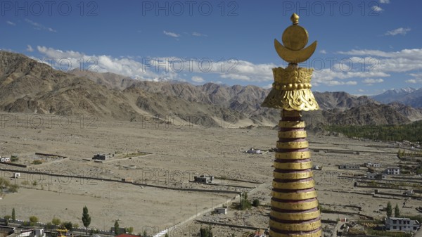 Golden stupa over a vast, mountainous landscape under a glowing sky, trekking in Ladakh, Himalayas,
