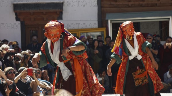 Two dancers in colorful costumes perform a traditional dance in front of an audience, Leh, Trekking