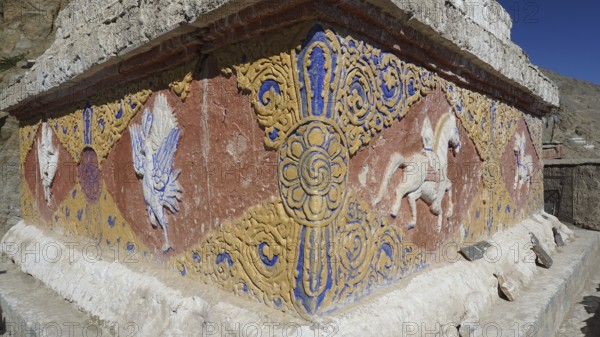 An artfully decorated relief with colorful patterns and symbols on a stone wall, Leh, trekking in