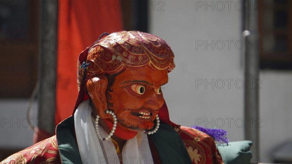 A vivid red-orange masked figure at a Buddhist ritual or dance in Leh, trekking in Ladakh,