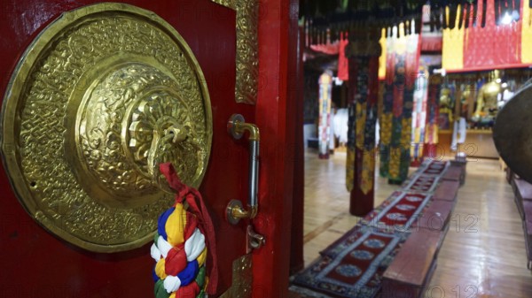 View through the imposing door, magnificent interior of a Buddhist temple with red carpets and