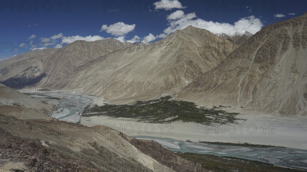 Extensive Nubra Valley with river course and impressive mountains under sunny skies, trekking in