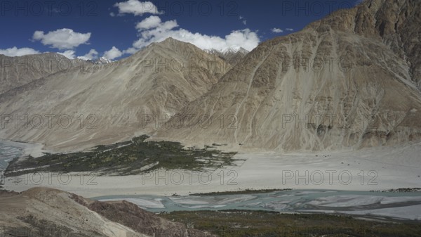 Nubra Valley, mountain valley with sand and river, surrounded by mountains under clear skies,