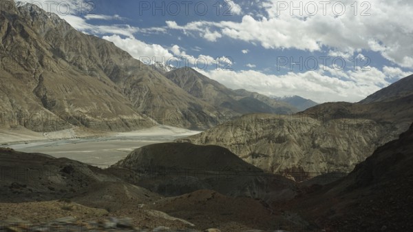 Wide mountain landscape under a cloudy sky with rocky slopes and a valley, trekking in Ladakh,