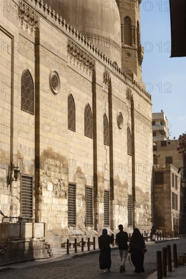 Local tourists walk past one of the many restored monuments along Sharia Al Muizz Li Din Allah near