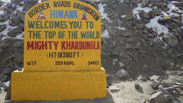 Colourful welcome sign at Khardungla Pass on rocky ground, trekking in Ladakh, Himalayas, India