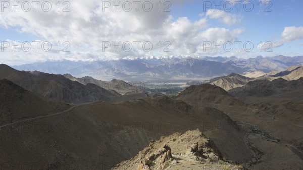 Extensive mountain landscape with sunny skies and stretches of clouds, trekking in Ladakh,