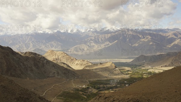 Mountain landscape with cloudy sky, snowy peaks in the background, trekking in Ladakh, Himalayas,