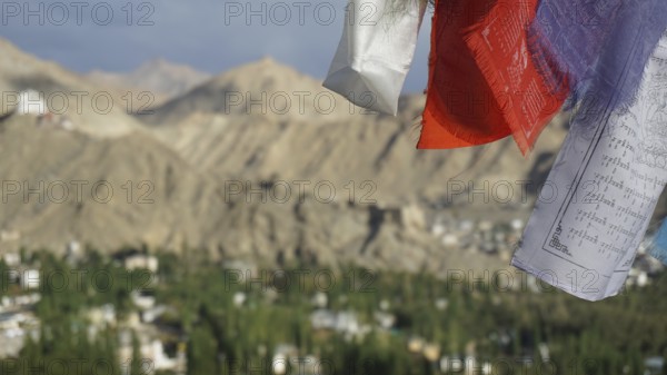 Close-up of prayer flags in foreground with mountain landscape in background under cloudy sky,