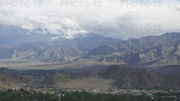Wide mountain landscape with cloudy sky and distant snow-capped peaks, trekking in Ladakh,