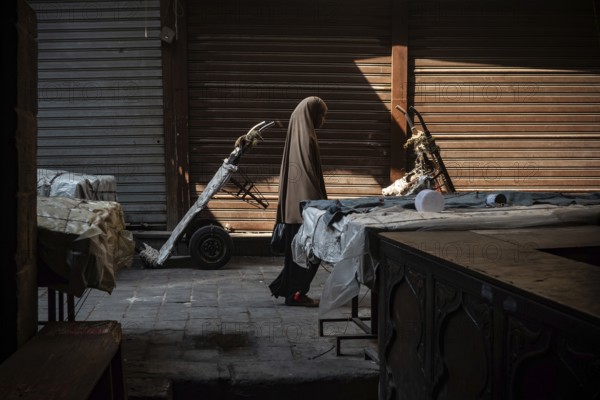 Cairo, Egypt. July 1st 2024 An Egyptian Muslim woman walks along the cobbled streets of a closed