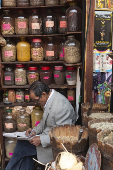 Cairo, Egypt. December 7th 2022 An Egyptian man doing a crossword while sitting in a spice shop in