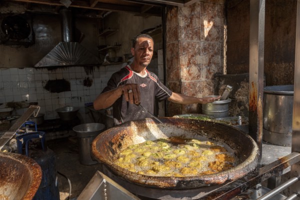 Cairo, Egypt. November 26th 2022 An Egyptian man deep frying Falafel, a chickpea and herb filled