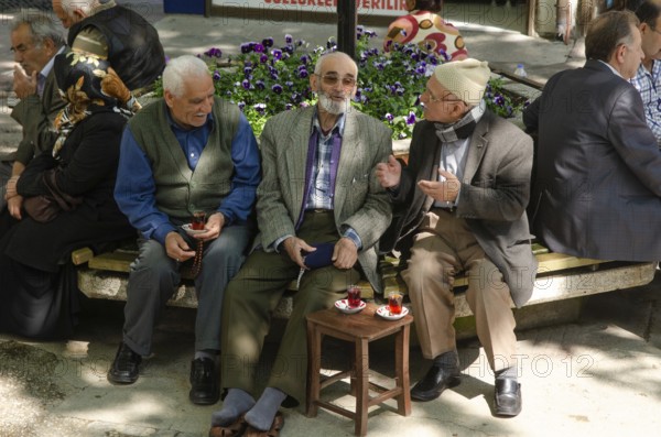 Bursa, Turkey. April 21st 2014 Old Turkish men chatting and drinking tea in a tree shaded square,