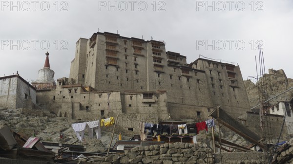 Large fortress complex, Leh Palace with hanging laundry, against cloudy sky, Ladakh, North India,