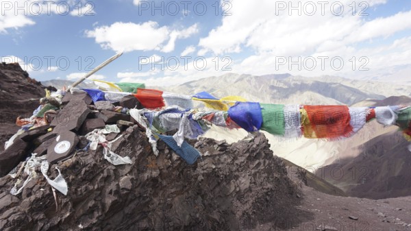 Colourful prayer flags flying over a rocky mountain landscape, trekking at Stok La Pass in Ladakh,