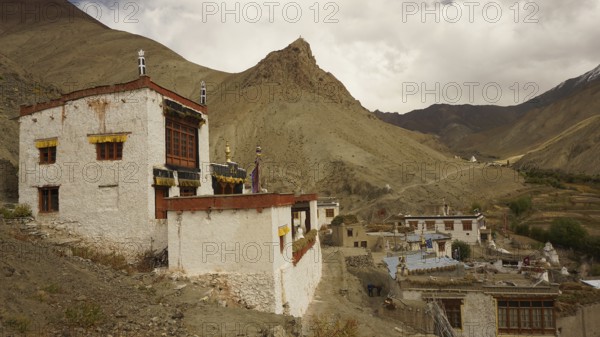 Traditional village on a mountainside under dramatic sky in the Himalayas, trekking in Ladakh,