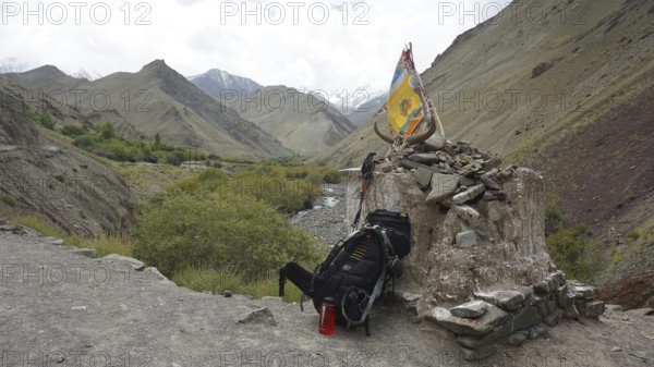 Place of worship with colorful flags and backpack in a mountainous landscape, break on a trekking