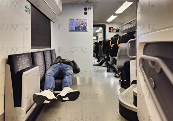 Sleeping man lying out early in the morning on the Wupper-Express RE 4 from National Express,
