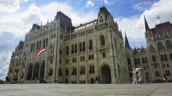 Parliament in Budapest, Impressive historic building in daylight with waving flag and people