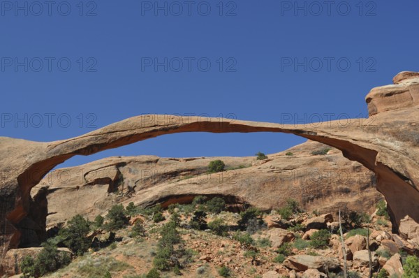 Landscape Arch, an impressive natural stone bridge against bright blue sky, Arches National Park,