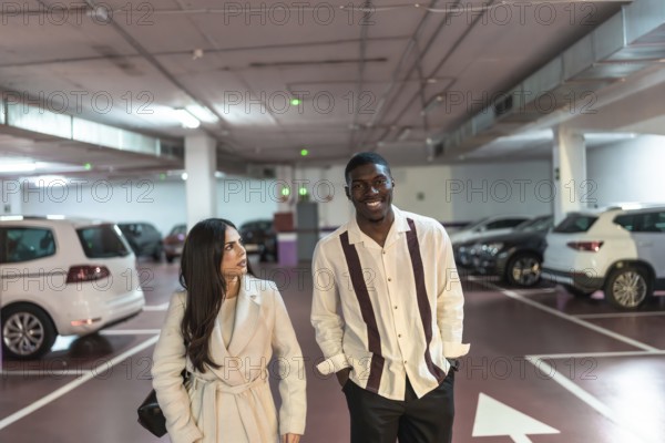 Young interracial couple walking and smiling together in an underground parking garage, looking