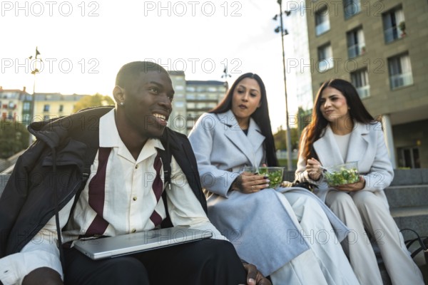 Diverse group of young adult colleagues or friends smiling and having a relaxed conversation while
