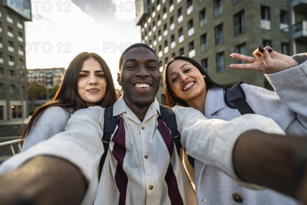 Three smiling multiracial friends enjoying an outdoor moment, capturing a joyful selfie together in